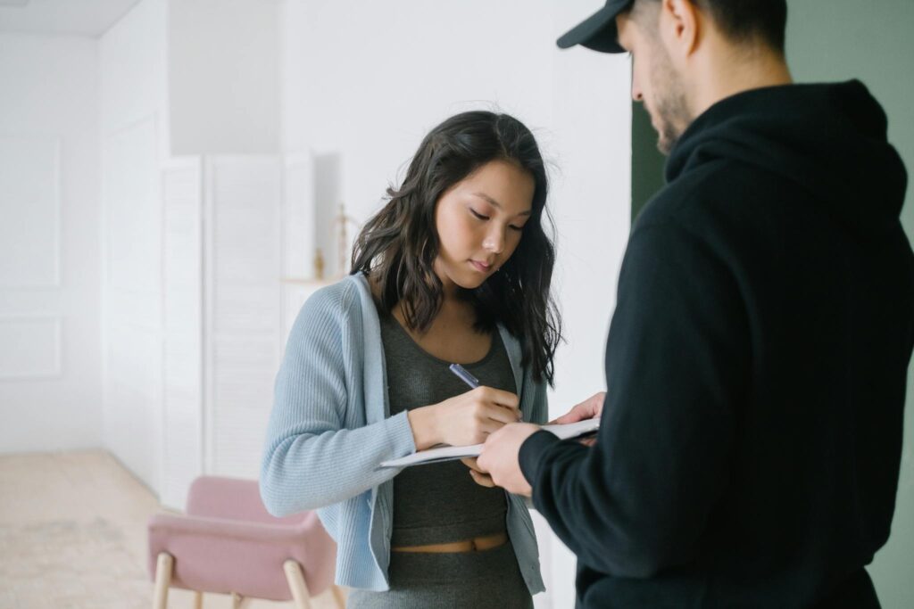 A Woman Writing on Paper Holding by the Man in Black Jacket